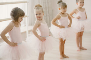 Cute little ballerinas in pink ballet costume. Children in a pointe shoes is dancing in the room. Kid in dance class.